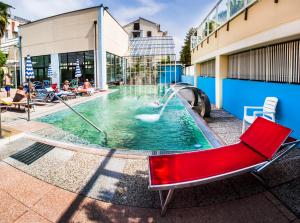 una piscina con una sedia rossa e una fontana di Hotel Al Sole Terme ad Abano Terme