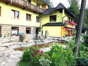 a yellow house with a pond in front of it at uKazika in Orawka