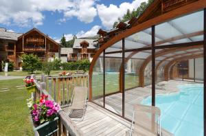 a deck with chairs and a swimming pool at Résidence Goélia L'Adret in Saint-Chaffrey