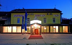 ein Gebäude mit zwei blauen Sonnenschirmen davor in der Unterkunft Apartments Klanac in Osijek