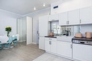 a kitchen with white cabinets and a dining room with a table at Elite Apartments Old Town Suite in Gdańsk