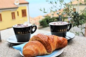 due tazze di caffè e un cornetto sul tavolo di Residenza Vinci Room & Suite a Pizzo