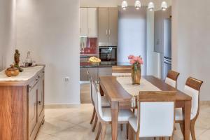 a kitchen with a wooden table and chairs and a vase with flowers at Villa Penelope in Kalpaki