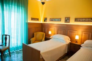 a hotel room with two beds and a chair at Hotel Palladio in Giardini Naxos