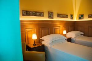two beds in a hotel room with two lamps at Hotel Palladio in Giardini Naxos