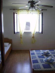 a bedroom with a ceiling fan and a window at Villa Welcome in Vrboska