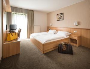 a hotel room with a bed and a suitcase at Hotel am Wald in Monheim