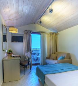 a bedroom with a bed and a desk and a couch at Cosmopolitan Hotel & Spa in Paralia Katerinis