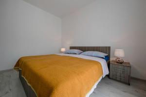 a bedroom with a large bed with a yellow blanket at Apartman Jasmina in Banjol