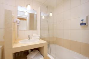 uma casa de banho branca com um lavatório e um chuveiro em Hotel le Sherpa em Les Deux Alpes
