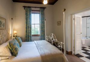 sypialnia z dużym łóżkiem i oknem w obiekcie Lord Milner Hotel w mieście Matjiesfontein