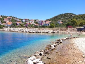 a group of people standing on a beach near the water at Astramaris Apartments in Okrug Donji