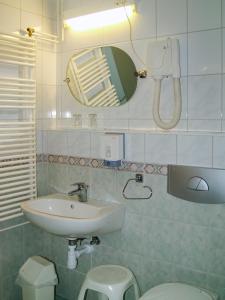 a bathroom with a sink and a toilet and a mirror at Hotel Nostra in Siófok