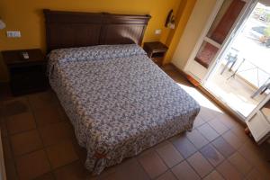 a bedroom with a bed with a wooden headboard and a window at La Palmosa in Alcalá de los Gazules