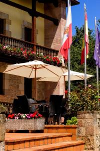 un patio con 2 sombrillas, sillas y flores en Hotel Los Angeles en Santillana del Mar