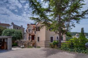 ein Haus mit einem Baum vor einer Einfahrt in der Unterkunft Filip Apartment in Mali Lošinj