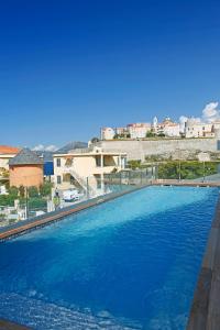 a large blue swimming pool with a city in the background at Hôtel Méditerranée in Calvi