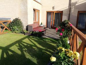 a backyard with a wooden deck with flowers and a bench at Apartamenty Wybrzeże Laguna II in Ustronie Morskie