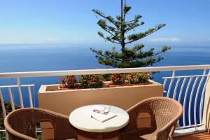 a table and chairs on a balcony with a christmas tree at Ocean Gardens in Funchal