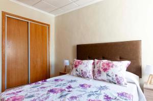 Schlafzimmer mit einem Bett mit rosa und lila Kissen in der Unterkunft Bungalow frente al mar in Torrevieja
