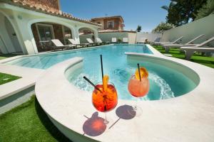 two cocktails sitting on a table next to a swimming pool at Suimi's Hotel in Villasimius