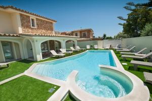 a swimming pool with chairs and a house at Suimi's Hotel in Villasimius