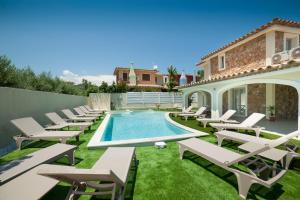 a patio with lounge chairs and a swimming pool at Suimi's Hotel in Villasimius