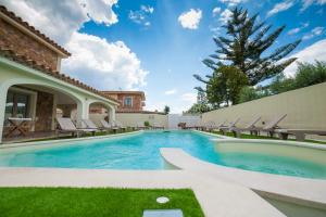a swimming pool with chairs and a house at Suimi's Hotel in Villasimius