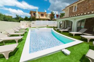 a backyard with a swimming pool with lounge chairs and a house at Suimi's Hotel in Villasimius