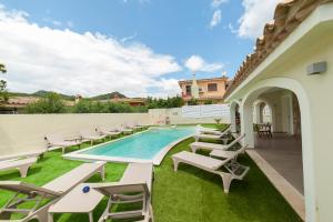 a patio with lounge chairs and a swimming pool at Suimi's Hotel in Villasimius