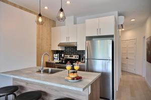 uma cozinha com armários brancos e um frigorífico de aço inoxidável em The Modern Cocoon em Quebeque