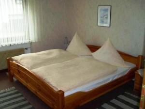 sypialnia z drewnianym łóżkiem z białą pościelą i poduszkami w obiekcie Ferienwohnung Am Limespfad w mieście Hesselbach