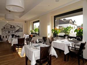 a restaurant with white tables and chairs and windows at Scheid´s Hotel – Restaurant in Wasserliesch