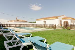 Villa con piscina y sillas en un patio en Casa Mariana en Conil de la Frontera
