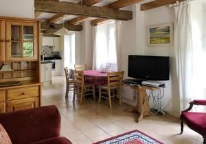 a living room with a table with a television and a kitchen at Val Rive - Le Pintadeau Cottage - Dinan in Dinan