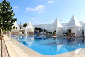 a large swimming pool with white tents and chairs at Tanger Med Hotel, Conference & Catering in Ghdar Defla