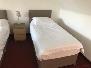two beds in a room with a white bedspread at The Barn Lodge in Stirling
