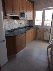 a kitchen with wooden cabinets and a sink and a microwave at Laredo-Colindres in Colindres