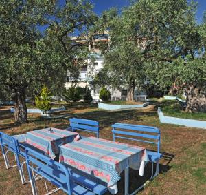 dos mesas azules y sillas en un parque con árboles en Panagiotis Hotel, en Skala Sotiros