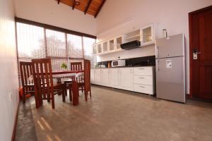 a kitchen with a table and chairs and a refrigerator at Hikka Boutique in Hikkaduwa