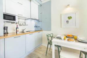 ポルトにあるSanta Catarina Modern Flatの白いキャビネットとテーブル(食べ物付)が備わるキッチン