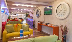 uma sala de estar com sofás amarelos e um relógio na parede em Tropical Hotel em Atenas