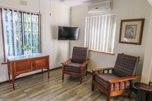 une salle d'attente avec deux chaises, un bureau et une télévision dans l'établissement Mtunzini BnB, à Mtunzini