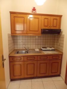 a kitchen with wooden cabinets and a sink at Studios Kentia in Skala Marion +91 photos