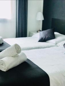 2 camas blancas con toallas en una habitación en Donjon B&B e Ristorante, en Someo