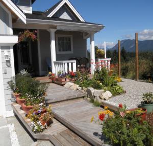 um alpendre de uma casa com um deque de madeira com flores em Above the Inlet em Sechelt