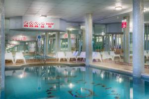 a swimming pool in a building with chairs and tables at Queens Hotel & Spa in Brighton & Hove