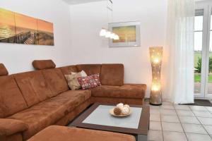 uma sala de estar com um sofá castanho e uma mesa em Ferienhaus Carolinenwind em Carolinensiel