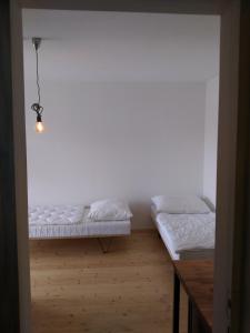 two beds in a room with white walls and wooden floors at Kůlna in Brod nad Dyjí