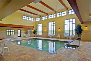 Una piscina en una habitación grande con sillas y mesas. en Country Inn & Suites by Radisson, Madison West, WI, en Middleton